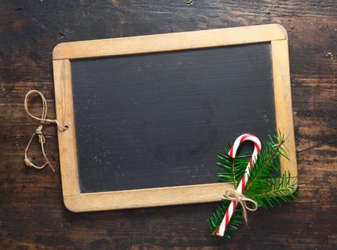 Small blank wooden framed chalkboard with a festive candy cane and greenery for your seasonal message for Christmas or New Year