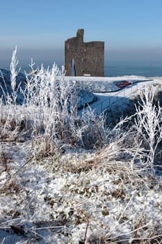 a seasonal snow covered view of atlantic ocean and ballybunion castle on a frosty snow covered winters day