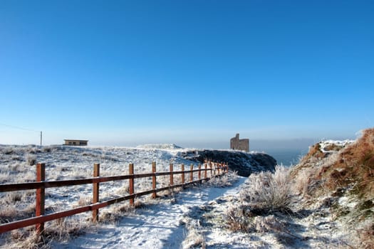 snow covered view of atlantic ocean and castle in ballybunion on a frosty snow covered winters day