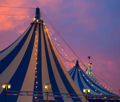 Circus tent in a dramatic sunset sky colorful orange blue with lights
