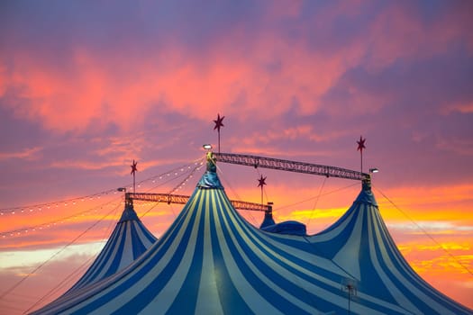 Circus tent in a dramatic sunset sky colorful orange blue with lights