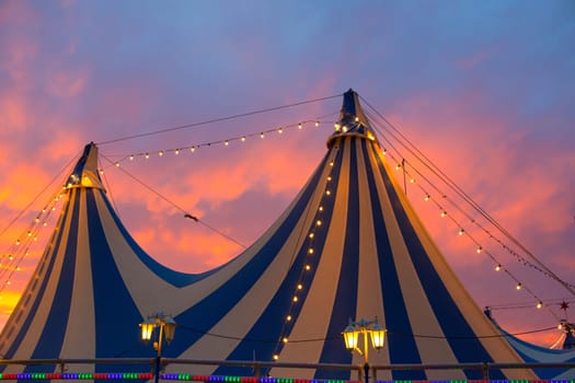 Circus tent in a dramatic sunset sky colorful orange blue with lights