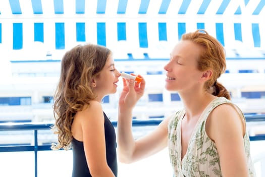 children girl with mother applying sunscreen in summer
