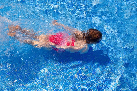 bikini kid girl swimming on blue tiles pool in summer vacation