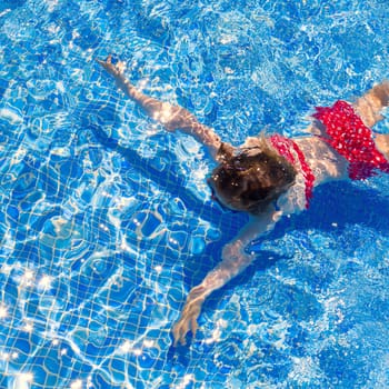 bikini kid girl swimming on blue tiles pool in summer vacation