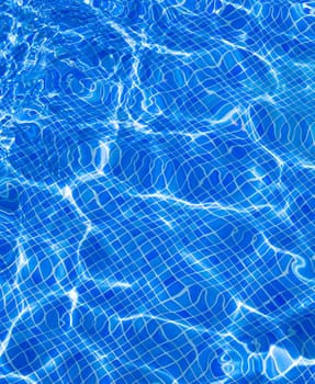 Blue tiles pool with ripple water reflection as a summer background