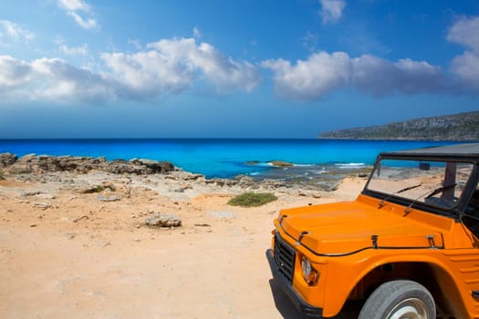 aqua formentera sea Es Calo with vintage retro orange car in Balearics