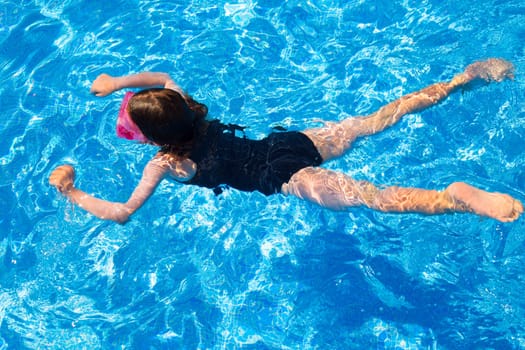 bikini kid girl swimming on blue tiles pool in summer vacation