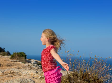 blue day with kid girl open hands to the wind and Mediterranean sea