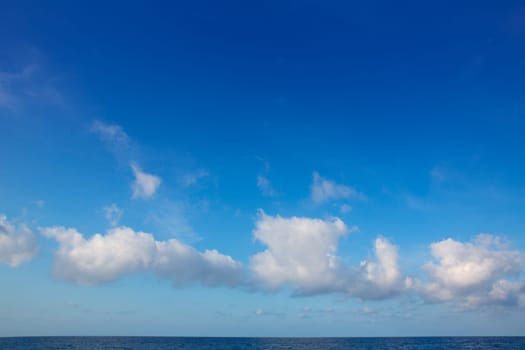 cumulus clouds in blue sky over ocean water horizon