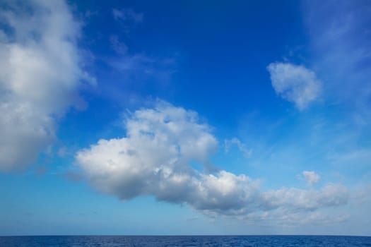 cumulus clouds in blue sky over ocean water horizon