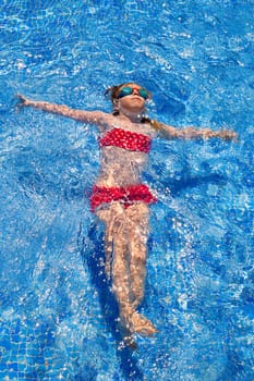 bikini kid girl swimming on blue tiles pool in summer vacation
