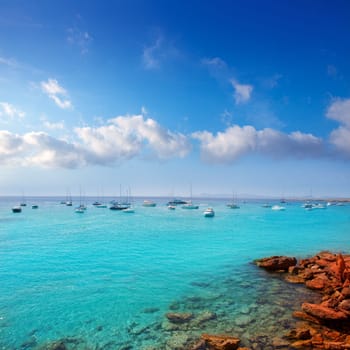 Cala saona in summer with many boats anchored in aqua Mediterranean