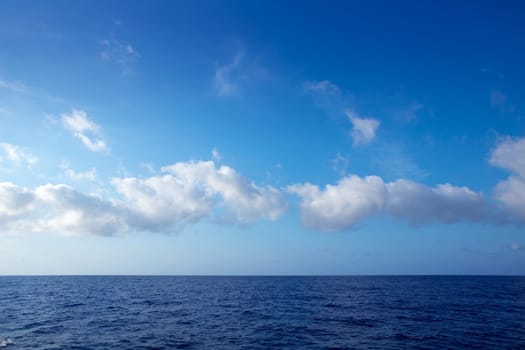 cumulus clouds in blue sky over ocean water horizon
