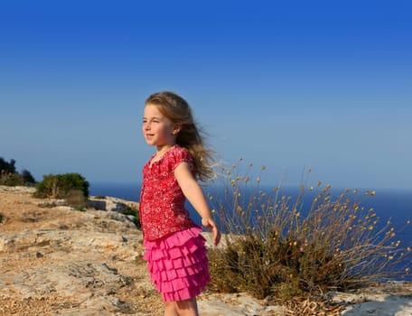 blue day with kid girl open hands to the wind and Mediterranean sea