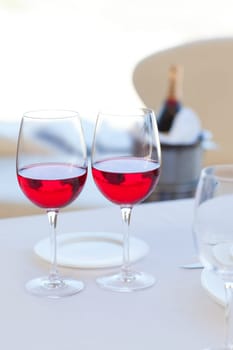 two cups of red wine and bottle in background on ice bucket
