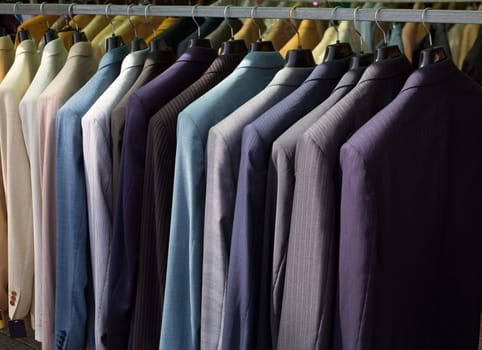 colorful male suits in row in a hanger as a pattern