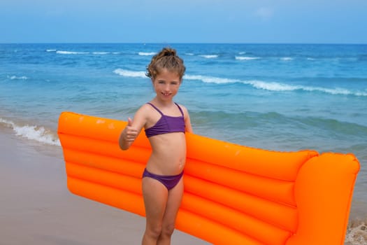 children kid girl standing in beach shore with orange floating lounge ok hand sign