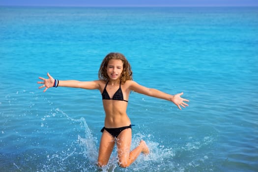 blue beach kid girl with bikini jumping and running splashing water