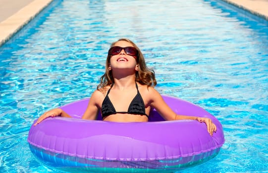 bikini kid girl with fashion sunglasses with purple inflatable pool ring