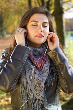 young woman listening music in park with earphones