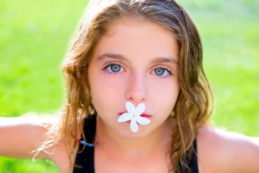 blue eyes children girl with jasmine flower in mouth at garden grass