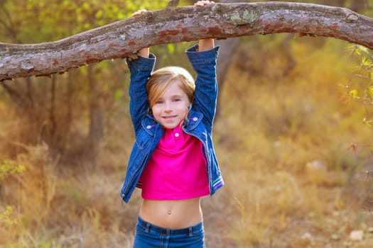 children girl swinging in a tree trunk in a pine forest