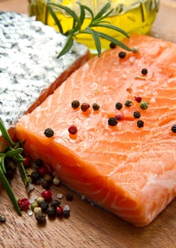 Fresh salmon fillet on wooden board with pepper and rosemary