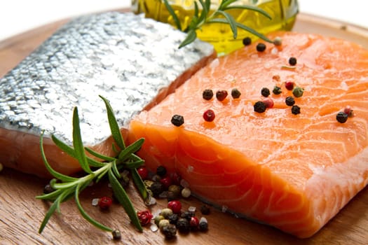 Fresh salmon fillet on wooden board with pepper and rosemary