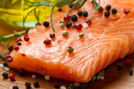 Fresh salmon fillet on wooden board with pepper and rosemary