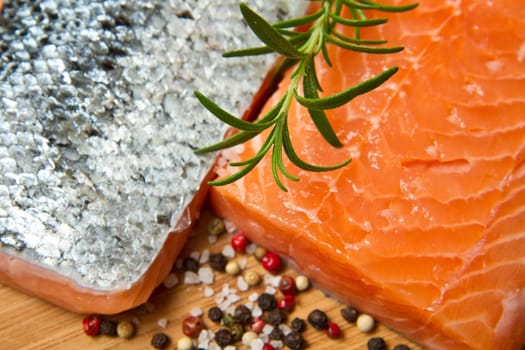Fresh salmon fillet on wooden board with pepper and rosemary
