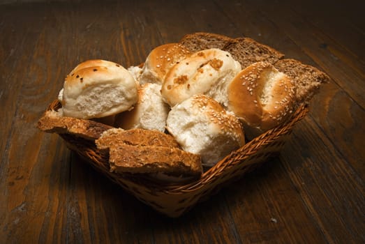 Delicious bread arrangement in basket on wooden table