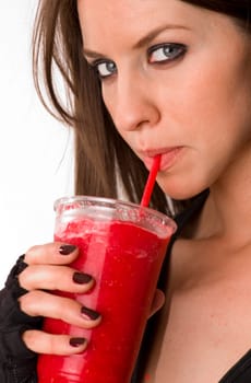 Attractive woman sips a red fruit smoothie through a straw