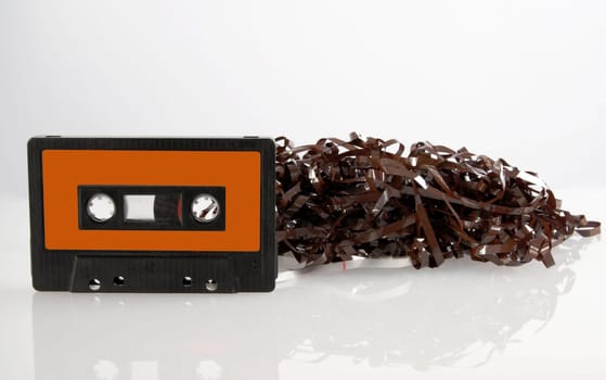 Single black audio cassette and tangled tape isolated with its reflection  on white background. Included clipping path, so you can easily cut it out and place over the top of a design.