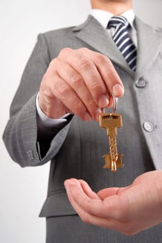 Businessman handing a key to success over a woman palm.