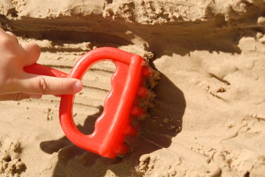 Summer concept: Kid hand playing with a toy at the beach.