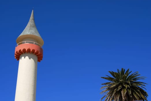 Tower and palm upper detail on blue sky background