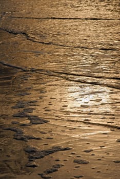 Golden waves texture under the light at dusk. Seashore at Malvin beach, Montevideo, Uruguay.
