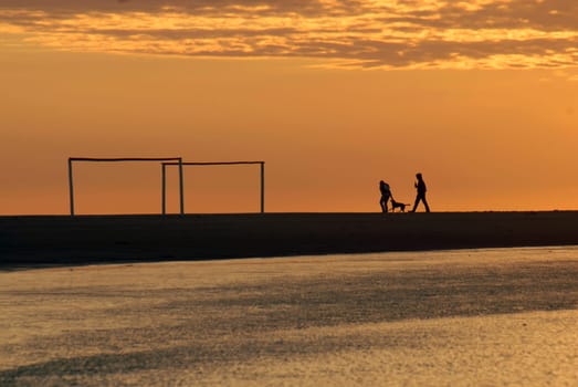 Beautiful golden sunrise seascape with soccer arcs and a running couple in the background. Montevideo, Uruguay