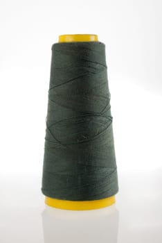 A bobbin of dark green thread isolated with its reflection on white background.  Included clipping path, so you can easily cut it out and place over the top of a design.