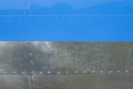 Airplane fuselage blue and silvel metal texture with rivets. Useful as background for design works.