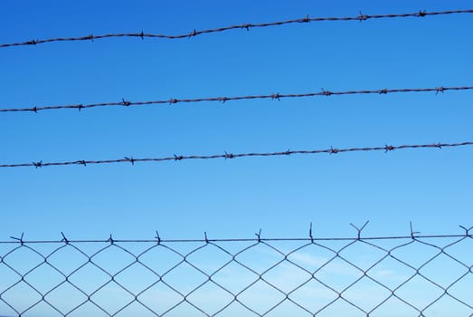 Cut wire fence with clear blue sky background.