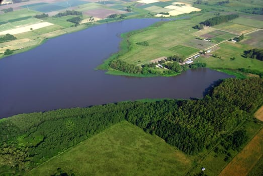 Aerial view of green agriculture meadows and a lagoon in Uruguay.