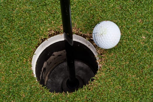 The golf holes, golf ball close to the hole.