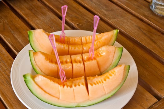 Yellow melon piece on a white plate.
