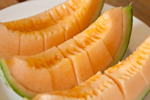Yellow melon piece on a white plate.