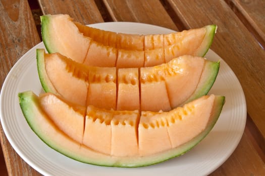 Yellow melon piece on a white plate.