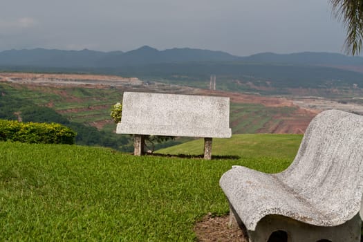 Cement bench on green grass and sky background