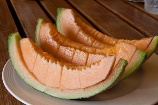 Yellow melon piece on a white plate.