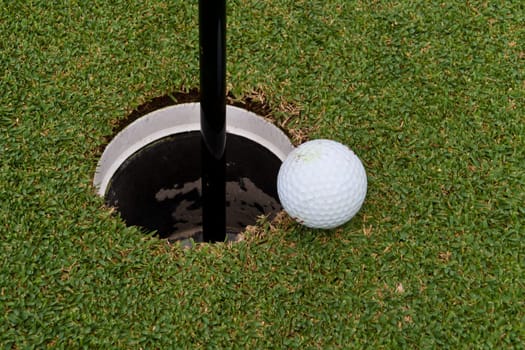 The golf holes, golf ball close to the hole.